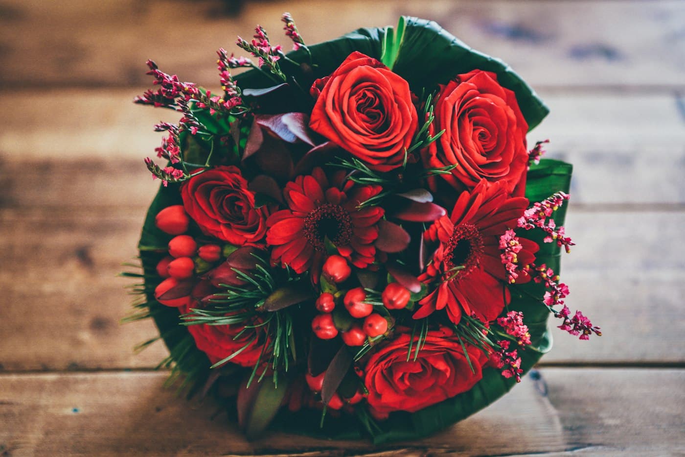 Bouquet de roses rouges et baies sur une table en bois